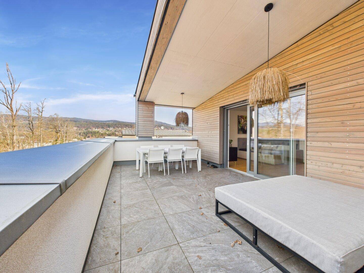 Geräumige Terrasse mit Essbereich, Liegefläche und weitem Blick in die malerische Landschaft.