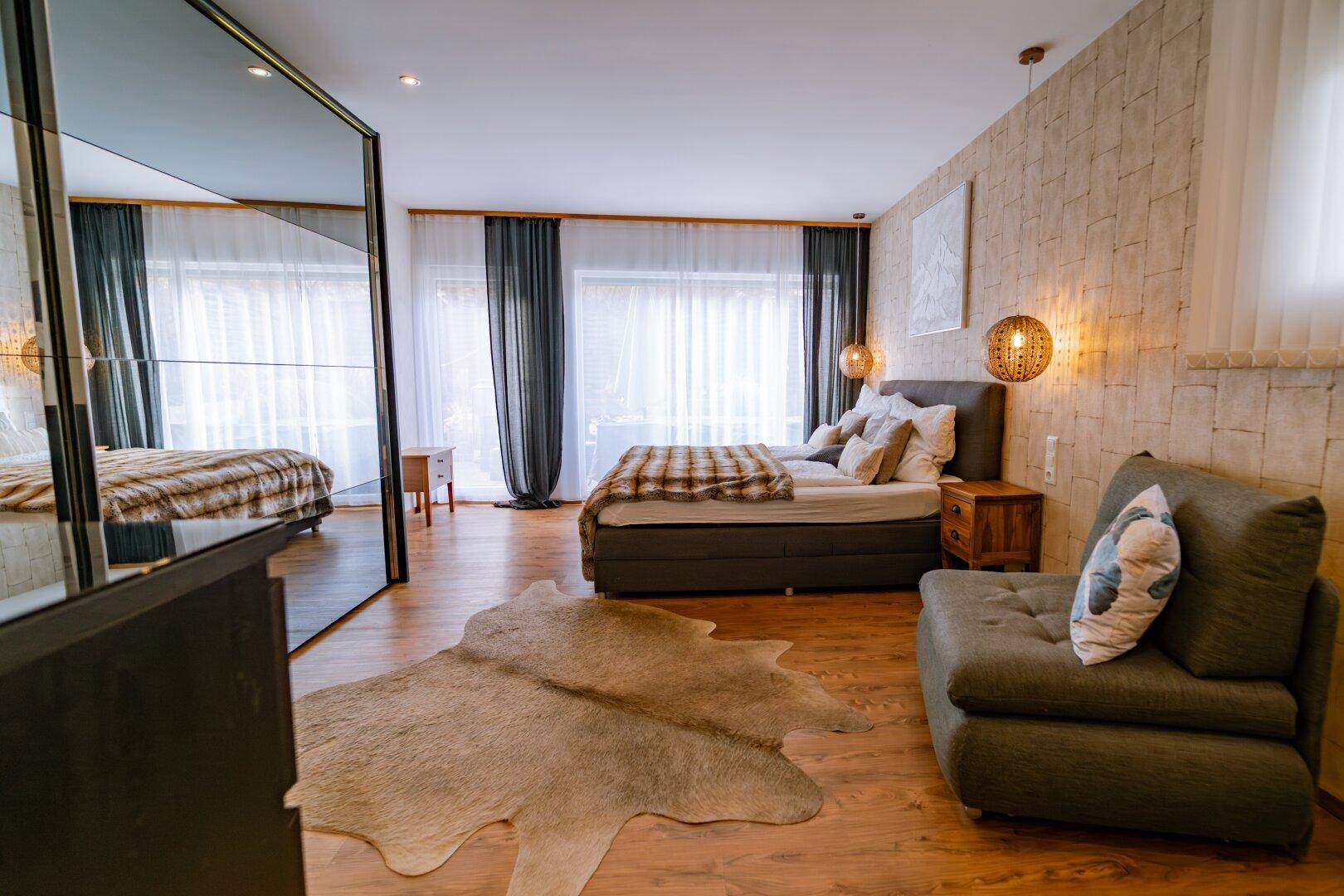 Geräumiges Schlafzimmer mit großem Bett, Spiegelwand und Holzboden.