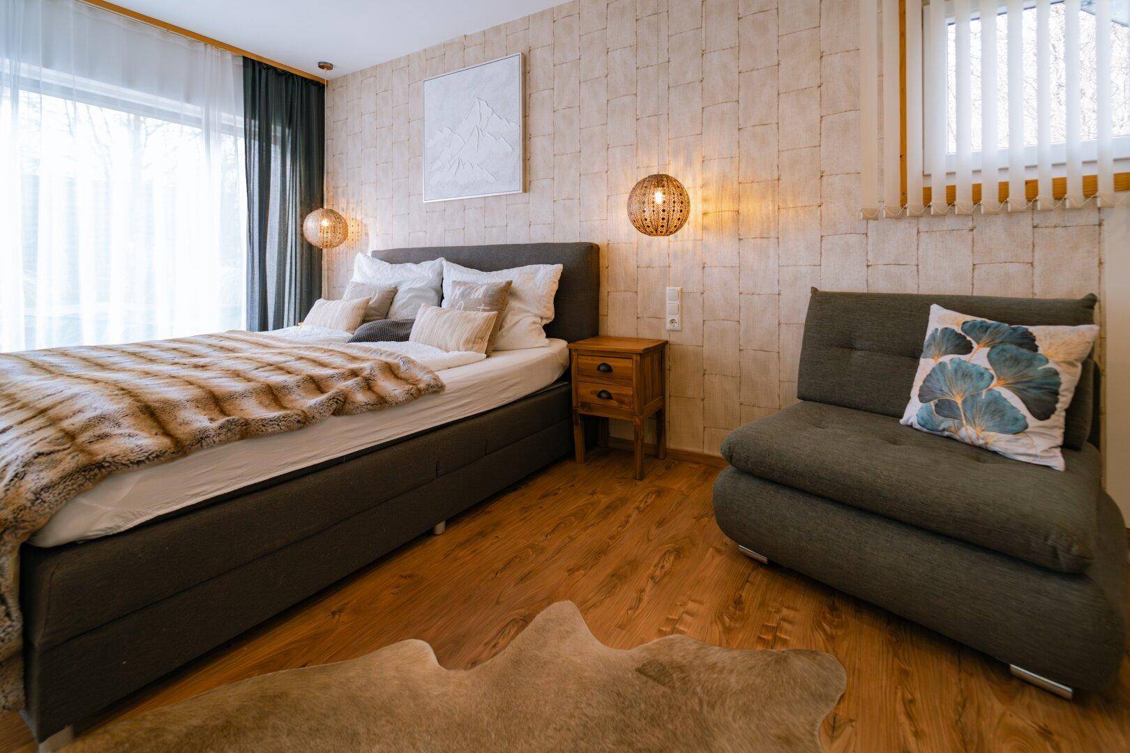 Gemütliches Schlafzimmer mit Doppelbett, Holzboden und strukturierten Tapeten.