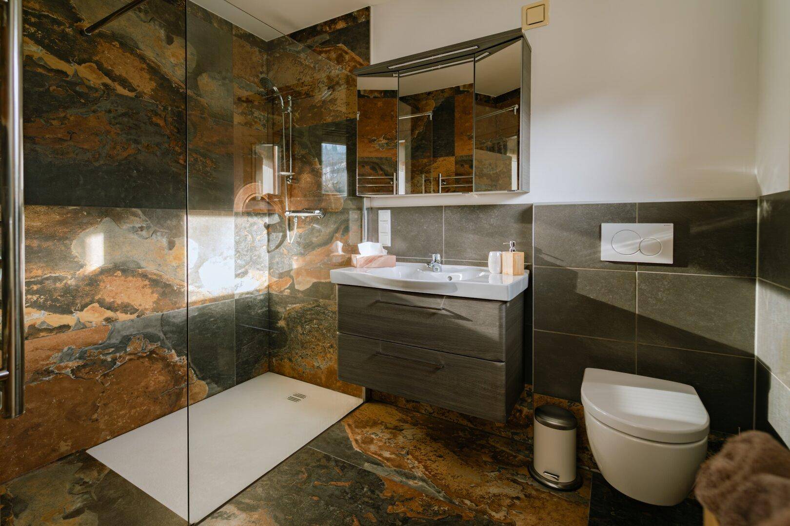 Modernes Badezimmer mit begehbarer Dusche, Waschtisch und Natursteinfliesen.