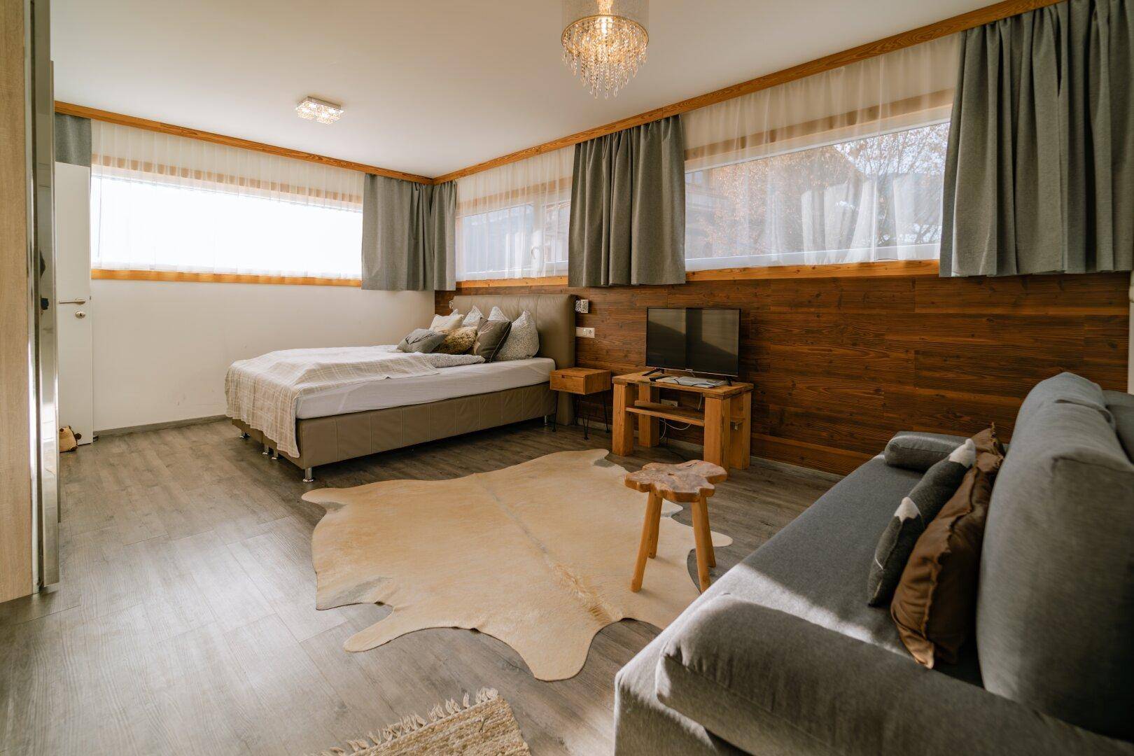Geräumiges Schlafzimmer mit Doppelbett, Sofa und Holzwandverkleidung.