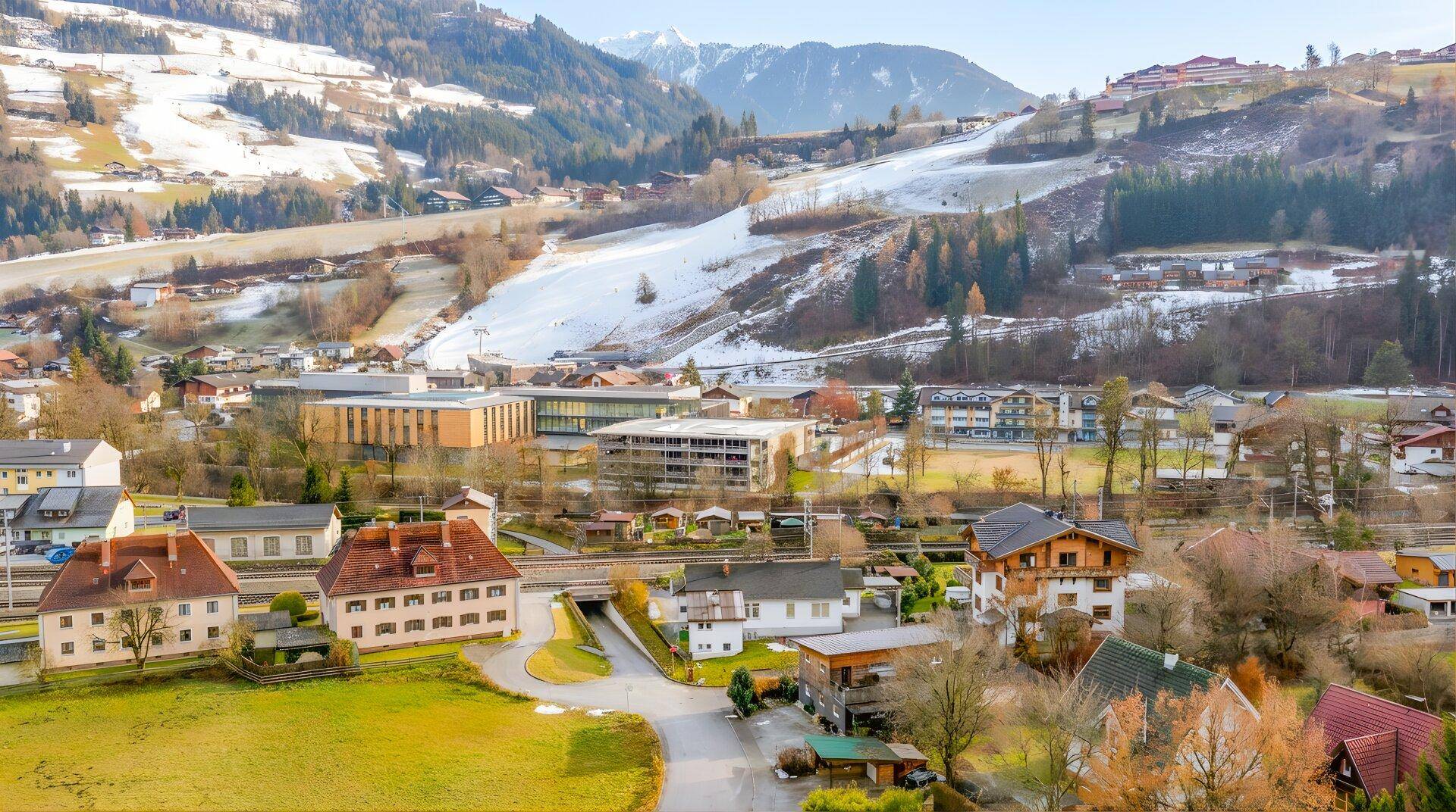 Panoramablick auf eine Siedlung mit schneebedeckten Hängen und Bergen.