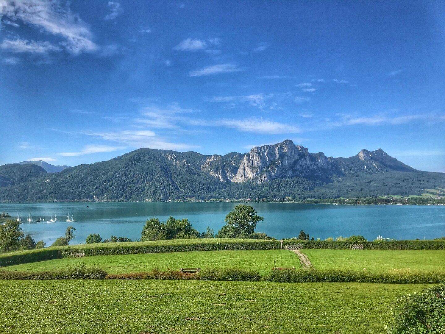 Weitläufige Grünfläche mit Panoramablick auf den See und die umliegende Berglandschaft.