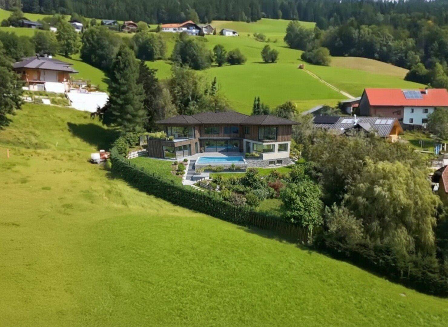 Luftaufnahme der modernen Villa in ländlicher Umgebung mit weiten Grünflächen und Nachbarhäusern.