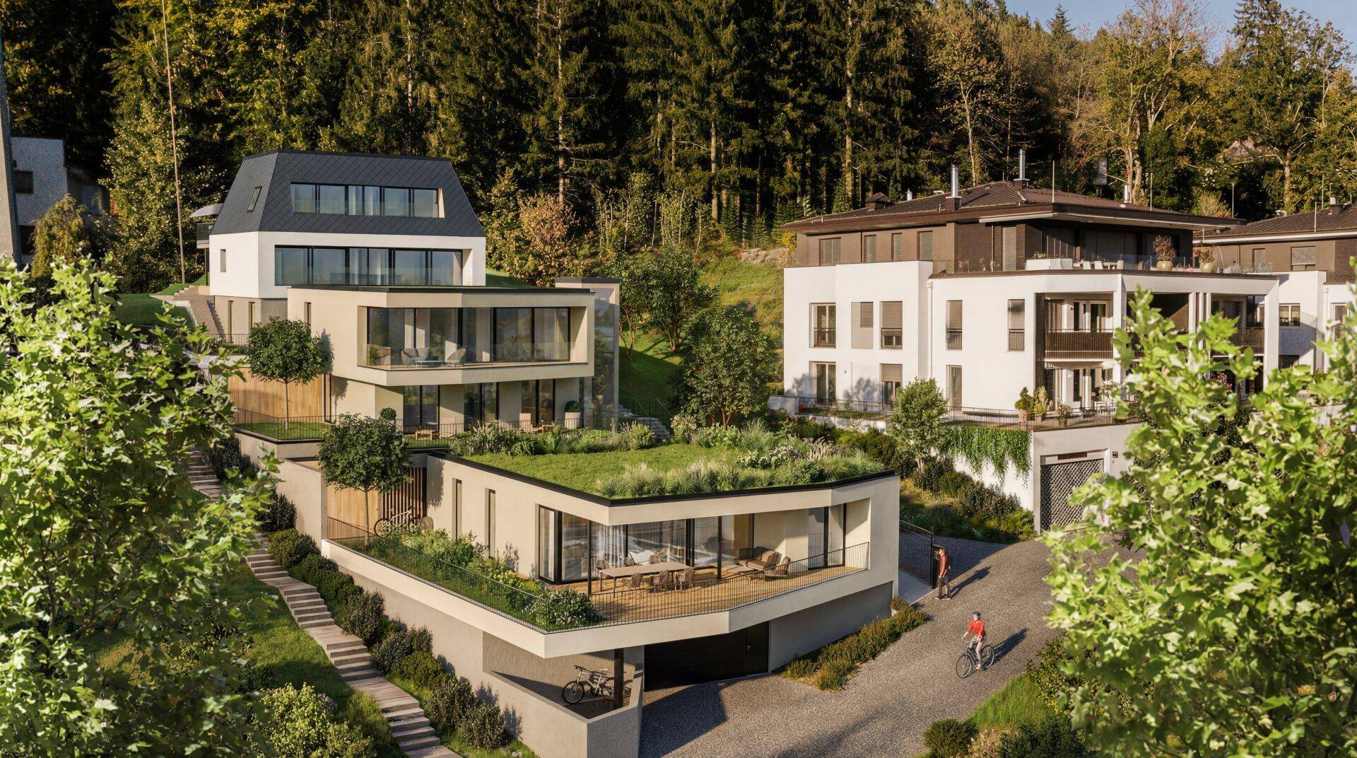 Moderne Wohnanlage mit mehreren Gebäuden, begrünten Dächern und umgeben von Wald.