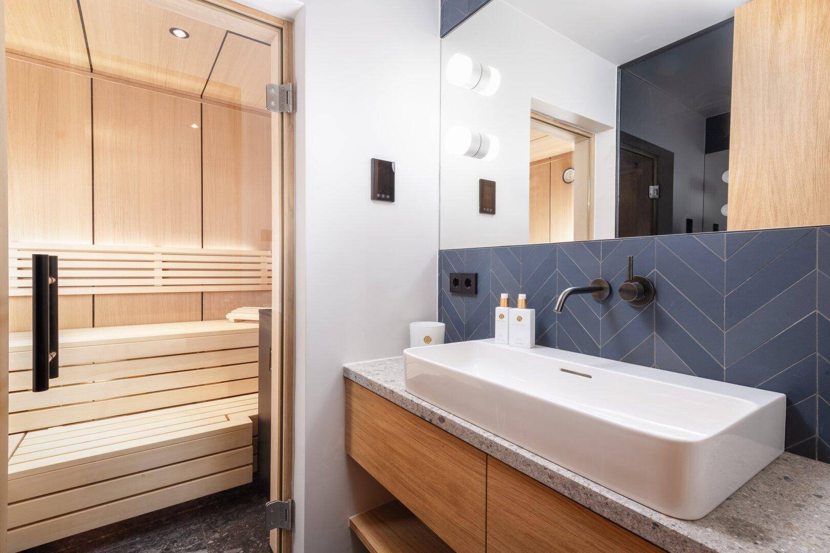 Modernes Badezimmer mit Sauna, Einzelwaschbecken und blauen Fliesen.