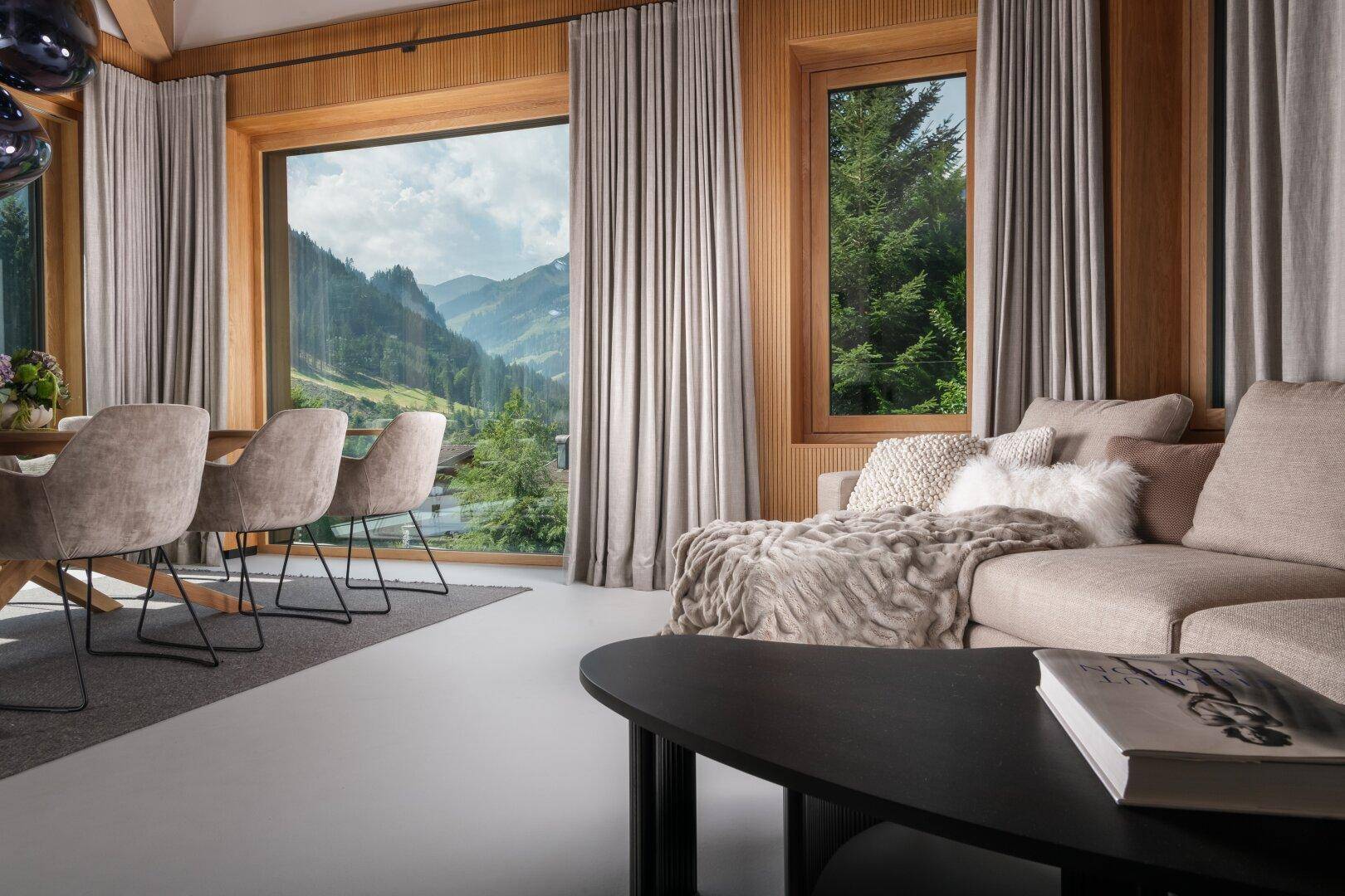 Offener Wohn- und Essbereich mit Bergblick und gemütlicher Sitzecke am Fenster.