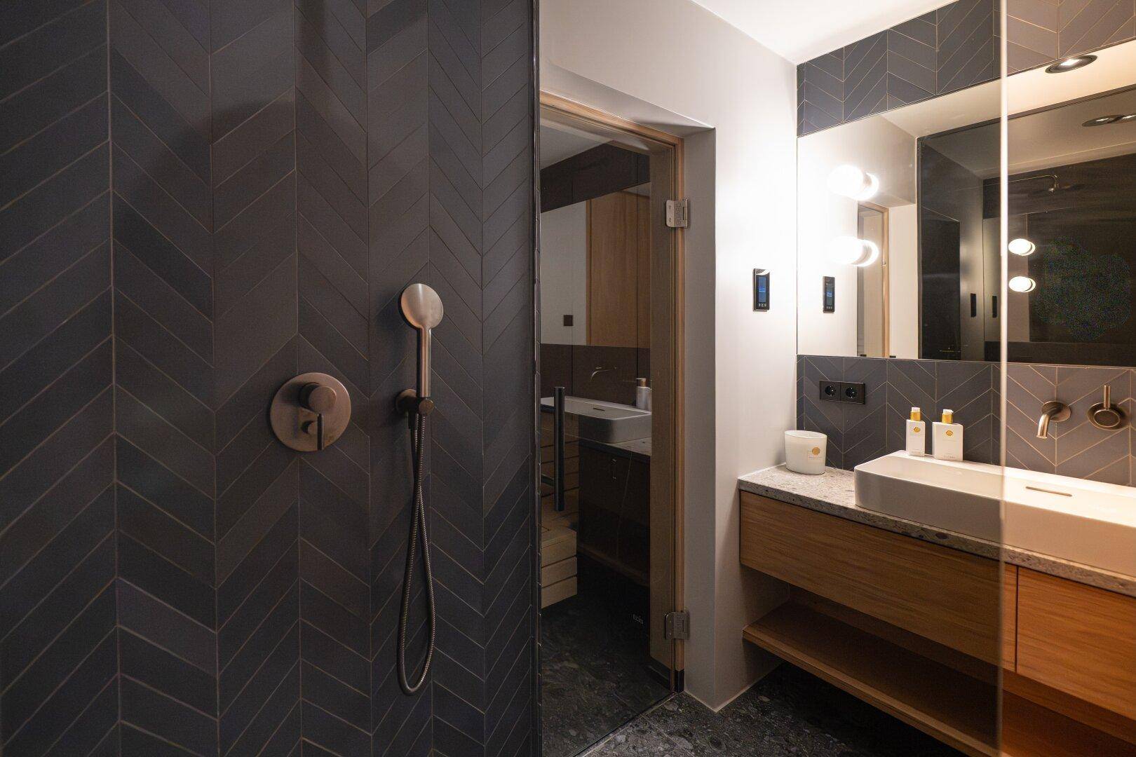 Modernes Badezimmer mit Duschbereich, Sauna und stilvollen Fliesen.