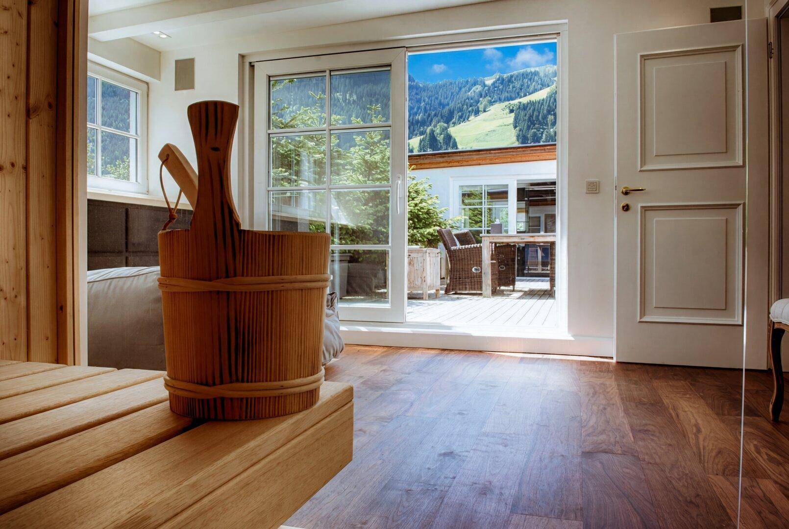 Traditionelle Holzsauna mit Eimer und Schöpfkelle, bietet direkten Zugang zur Terrasse und Bergblick.