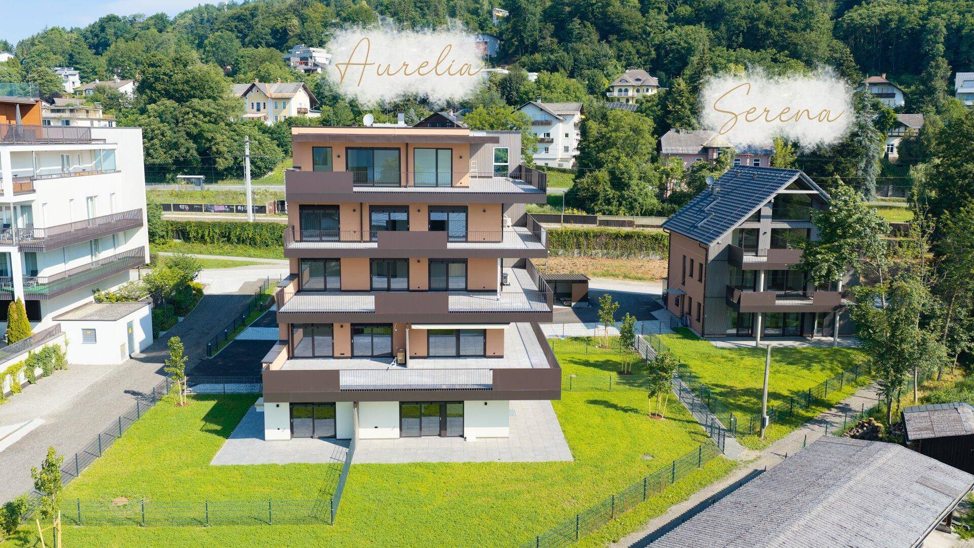 Luftaufnahme von zwei modernen Apartmentgebäuden mit Balkonen und gepflegten Grünflächen.