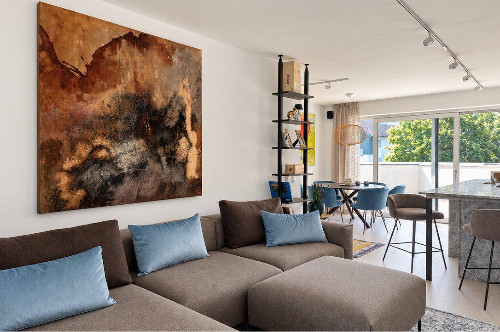 Gemütlicher Wohnbereich mit großem Sofa, moderner Kunst und offenem Übergang zum Essbereich.