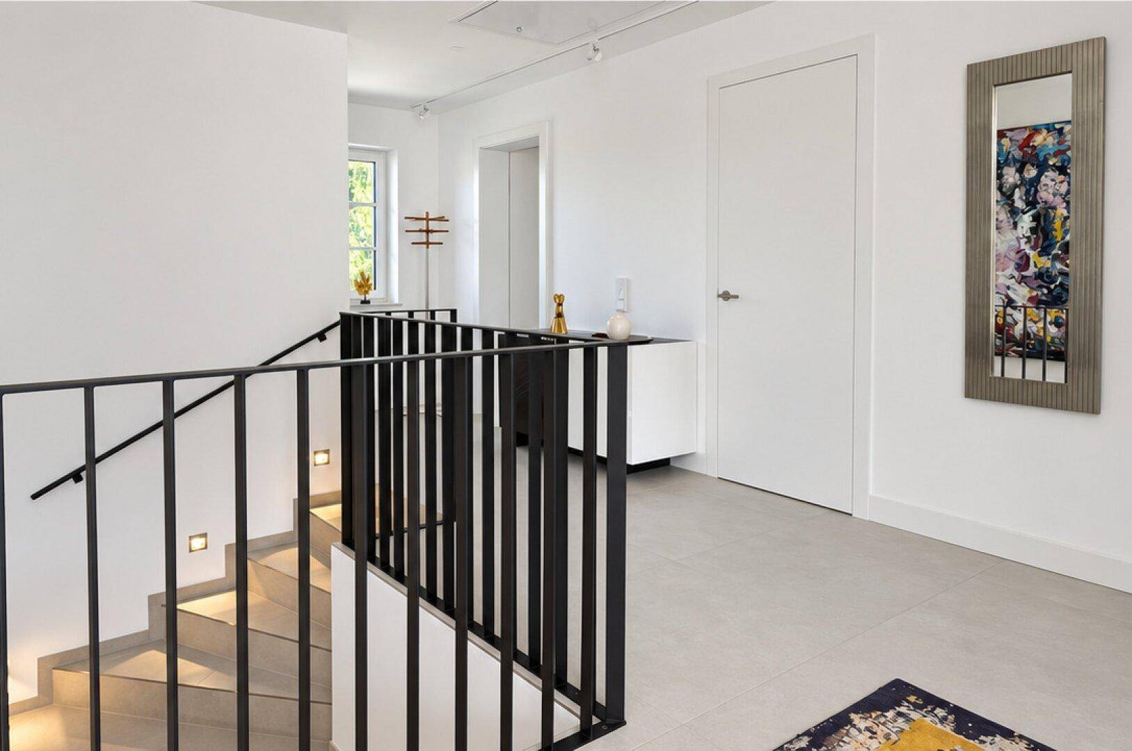 Heller Flur mit moderner Treppe, minimalistischem Design und indirekter Beleuchtung.
