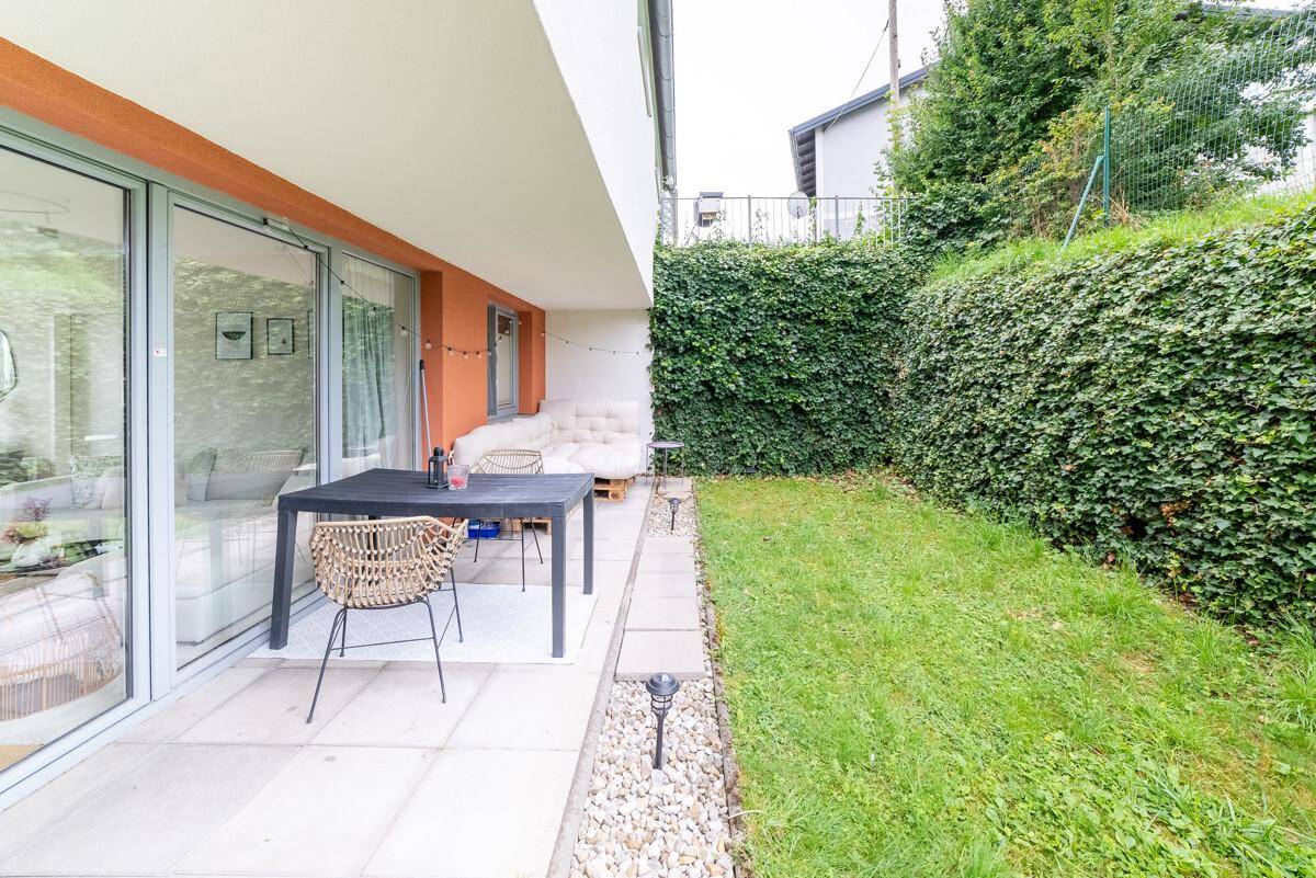 Geräumige Terrasse mit Esstisch und Stühlen, angrenzend an einen gepflegten Gartenbereich.