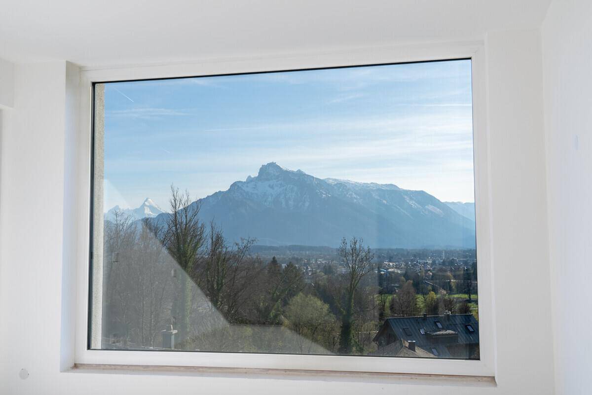 Große Fensterfront bietet einen weiten Blick auf die schneebedeckten Berge und die umliegende Landschaft.