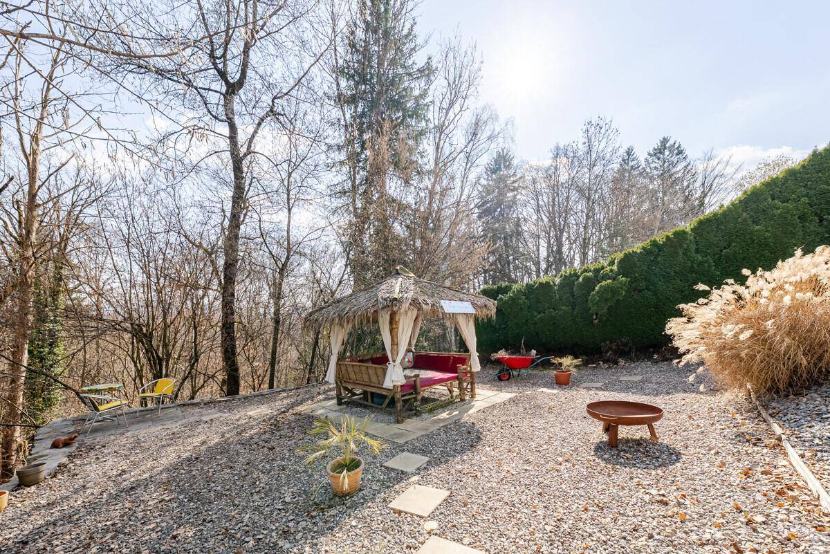 Entspannender Kiesgarten mit Stroh-Pavillon, Feuerstelle und Blick ins Grüne.