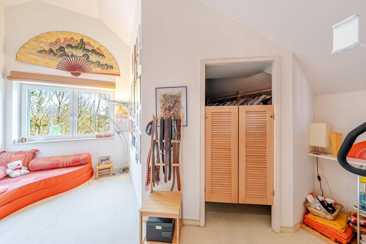 Gemütlicher Wohnbereich mit Sofa, Fenster und integriertem Schrank unter der Dachschräge.
