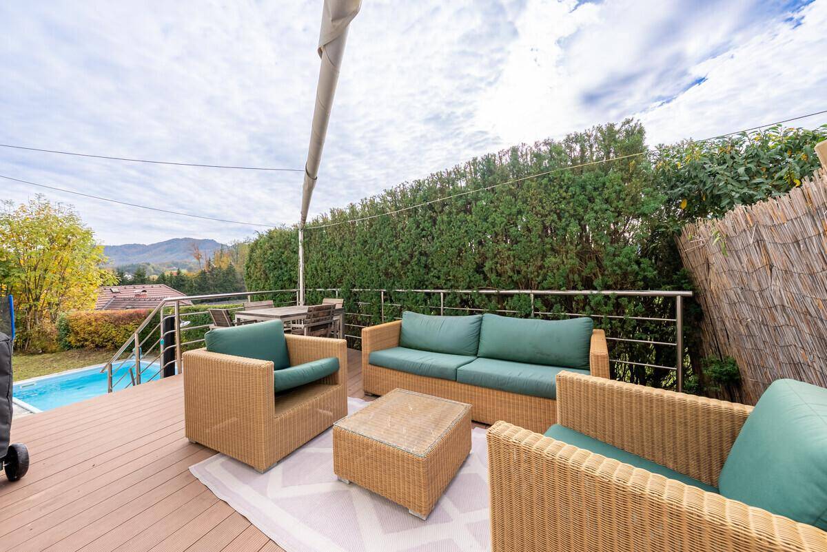 Geräumige Terrasse mit Rattanmöbeln und Blick auf den Pool und die umliegende Landschaft.
