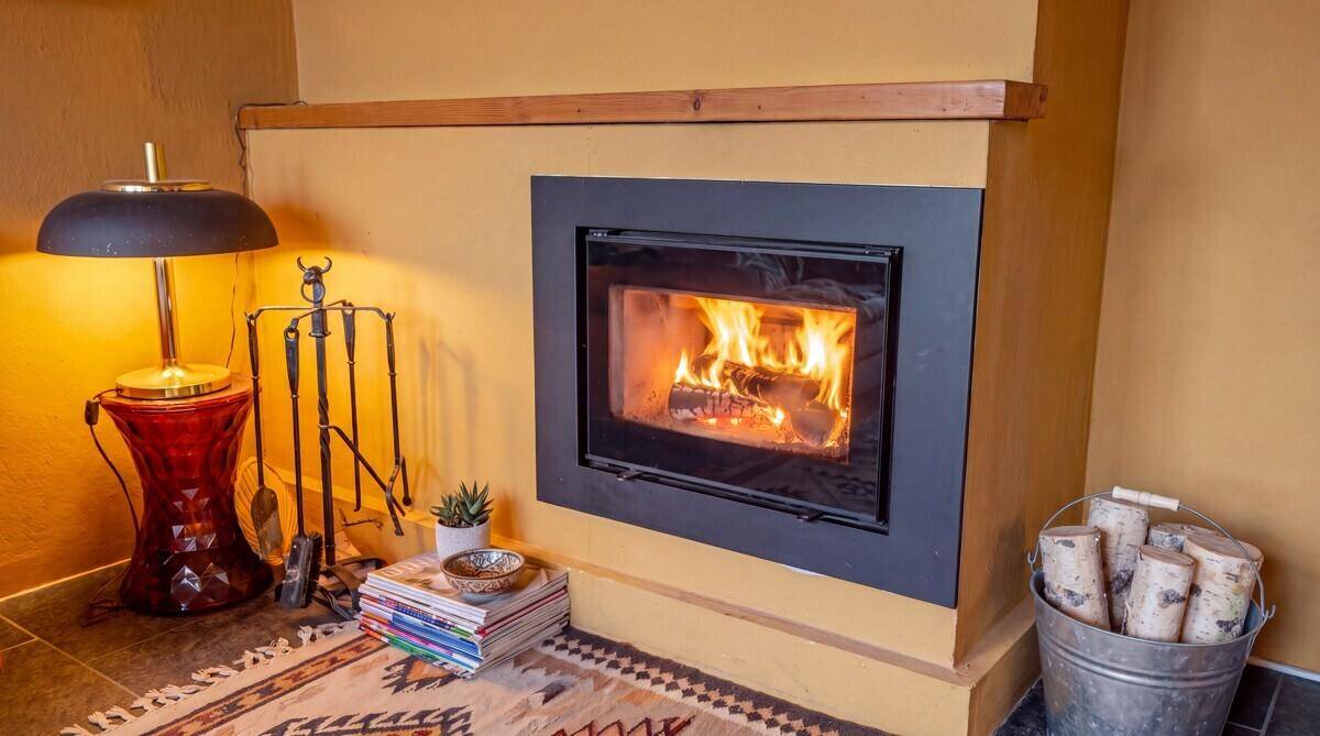 Gemütlicher Kamin mit brennendem Holz, umgeben von rustikalen Elementen und warmem Licht.