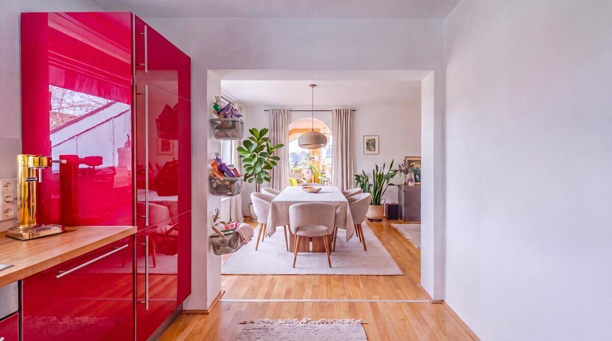 Moderne Küche mit leuchtend roten Hochglanzschränken, offen zum eleganten Essbereich.
