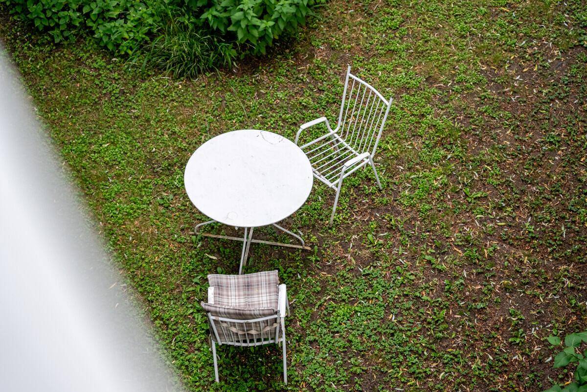 Kleiner Sitzbereich im Garten mit weißem Tisch und Stühlen, von oben gesehen.