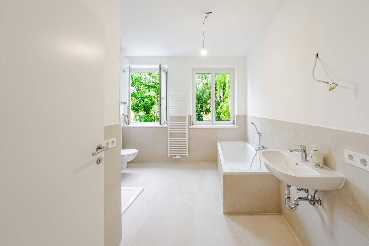 Modernes Badezimmer mit Badewanne, Dusche, Einzelwaschbecken und Fensterblick ins Grüne.
