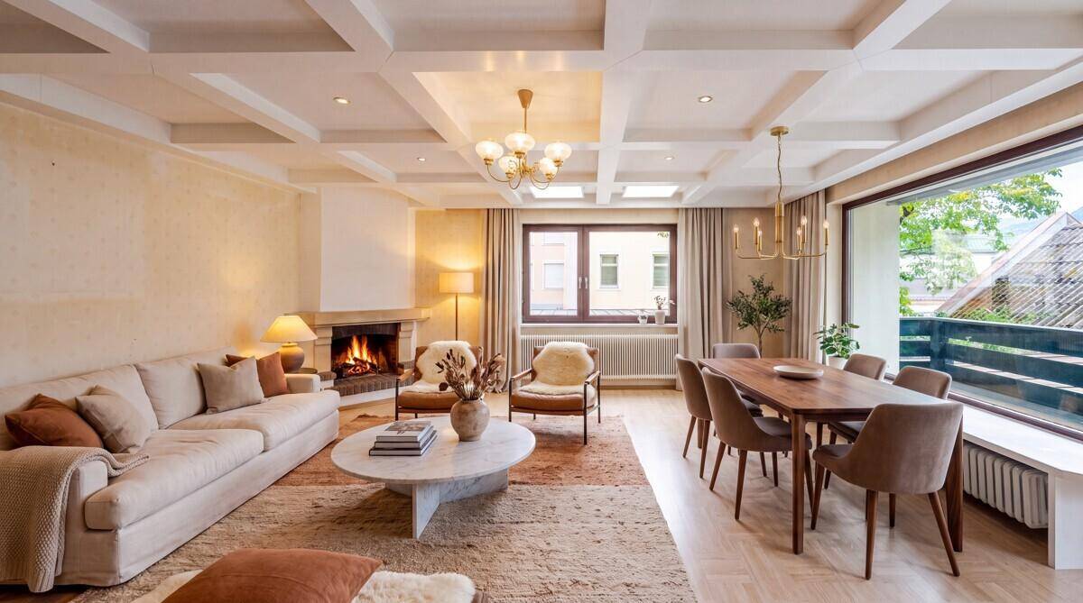 Eleganter Wohn-Essbereich mit Kamin, Kassettendecke und großen Fenstern.