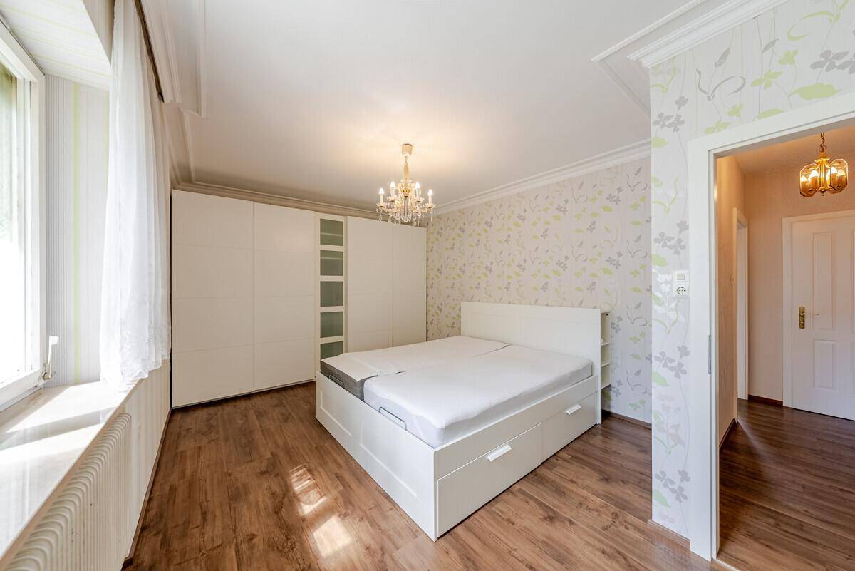 Helles Schlafzimmer mit Holzboden, großem Kleiderschrank und dekorativer Tapete.