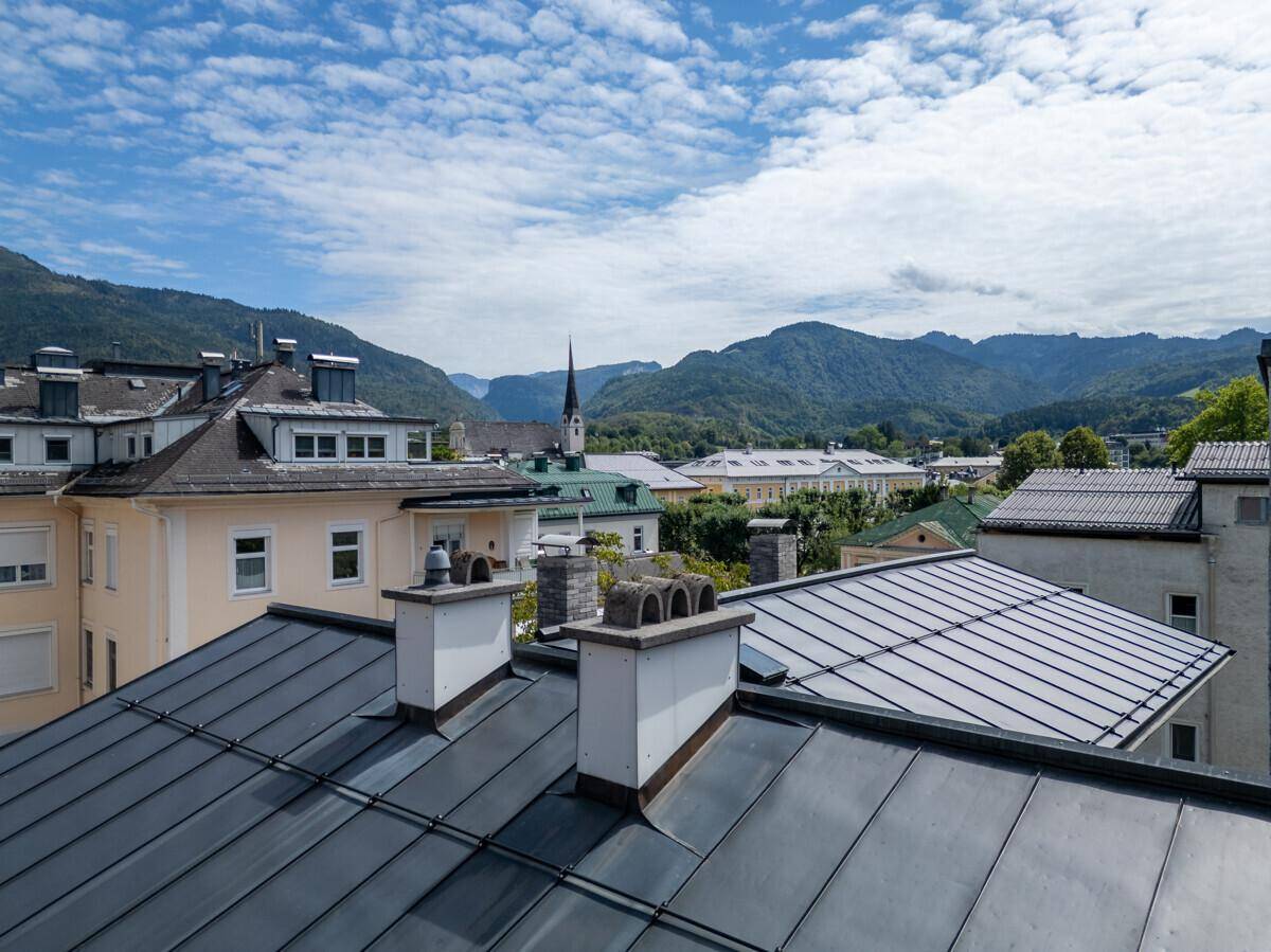 Panoramablick über die Dächer der Stadt mit majestätischen Bergen im Hintergrund.