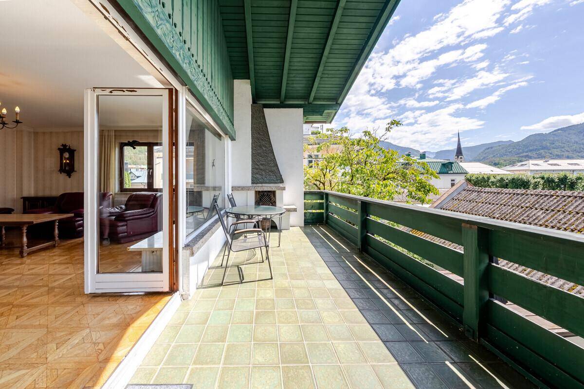 Geräumiger Balkon mit Sitzgelegenheiten, Fliesenboden und Blick auf die Umgebung.