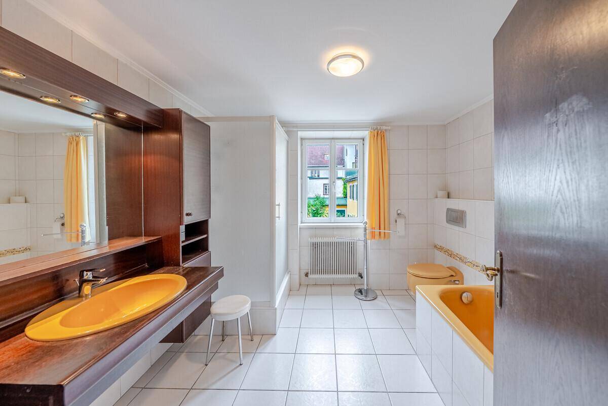 Geräumiges Badezimmer mit gelber Badewanne, Doppelwaschbecken und Fenster.