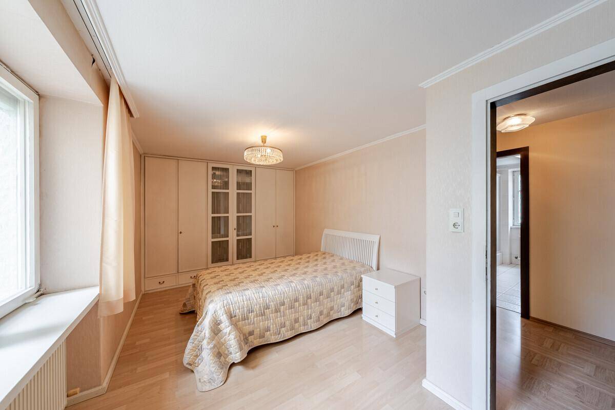 Gemütliches Schlafzimmer mit hellem Laminatboden, Einbauschränken und großem Fenster.