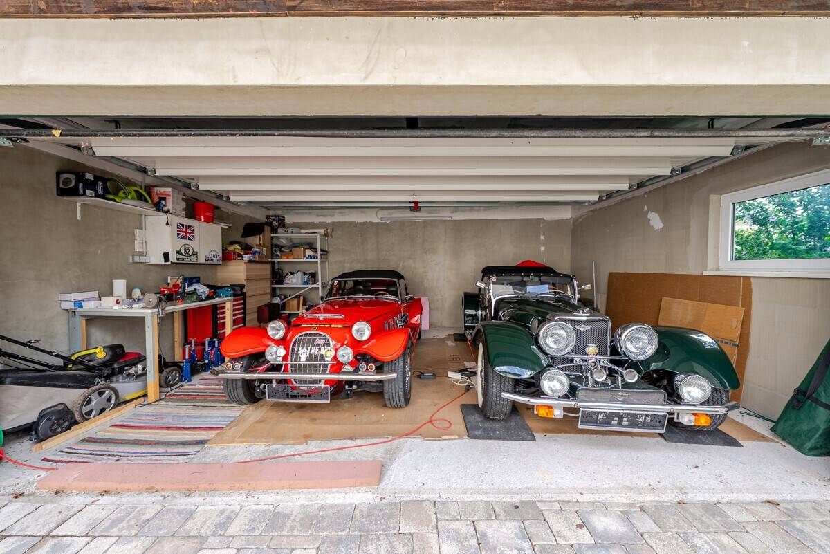 Geräumige Garage mit zwei Oldtimern, Stauraum und einem Fenster für Tageslicht.