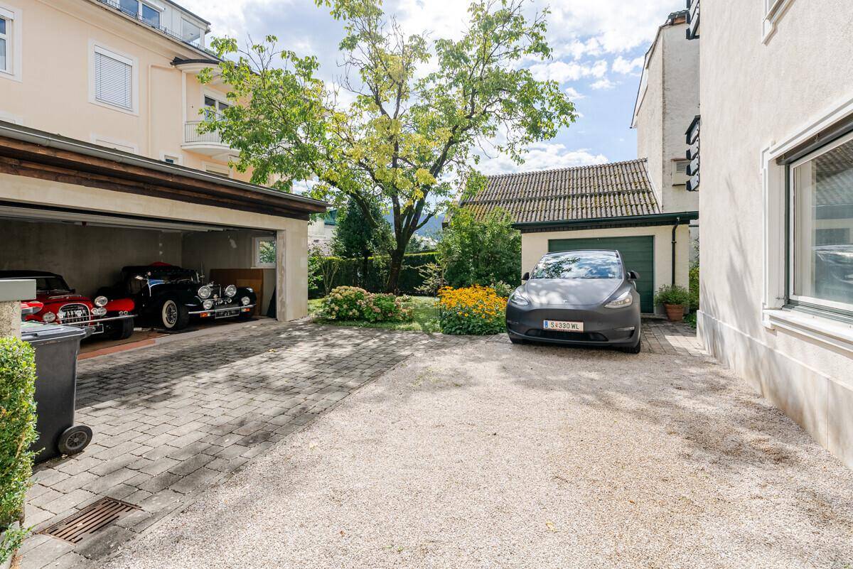 Geräumiger Hofbereich mit Parkplätzen, einer Garage und einem großen Baum im Hintergrund.