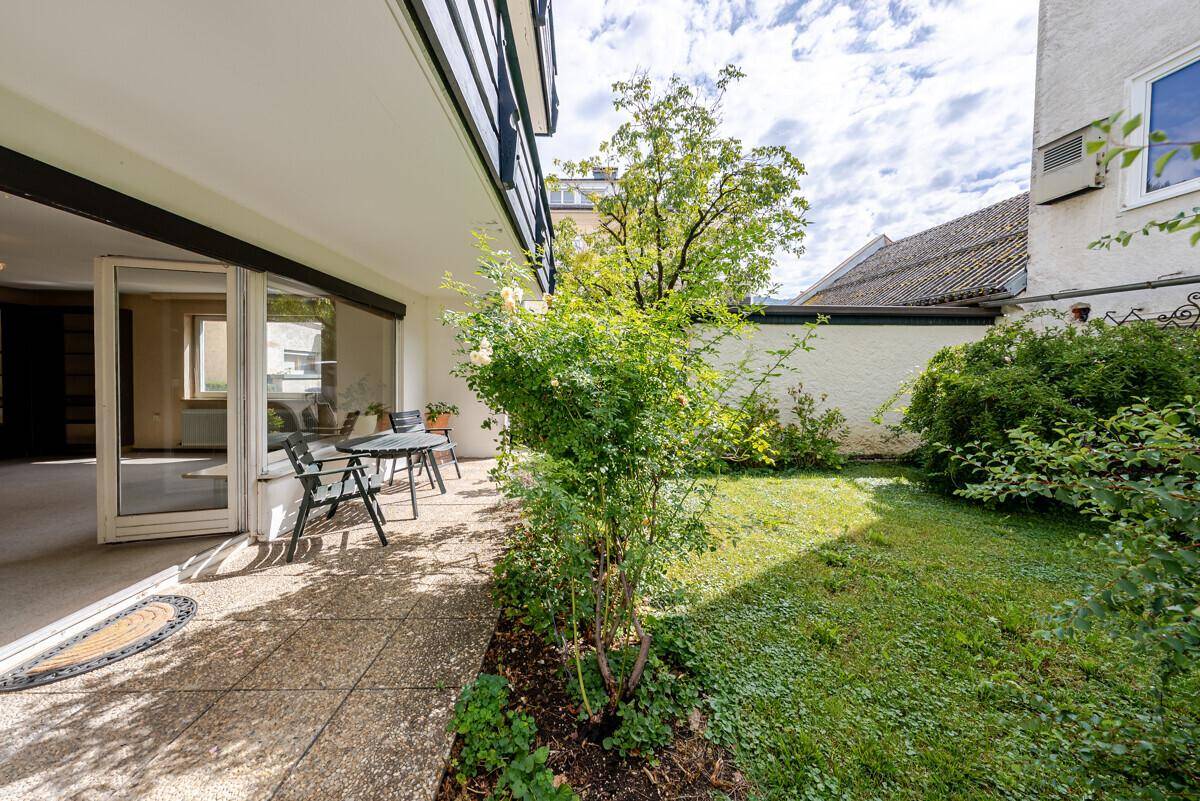 Sonniger Terrassenbereich mit Sitzgelegenheiten und direktem Zugang zum grünen Garten.