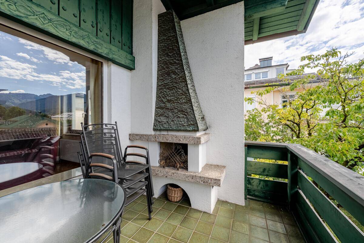 Balkon mit Außenkamin, Sitzgelegenheiten und Blick auf die umliegende Landschaft.