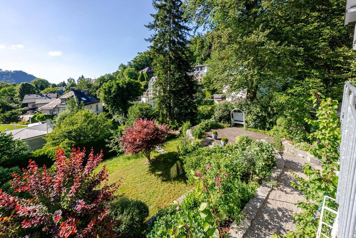 Blick von oben auf den weitläufigen Garten mit Rasenflächen, Bäumen und verschiedenen Pflanzen.
