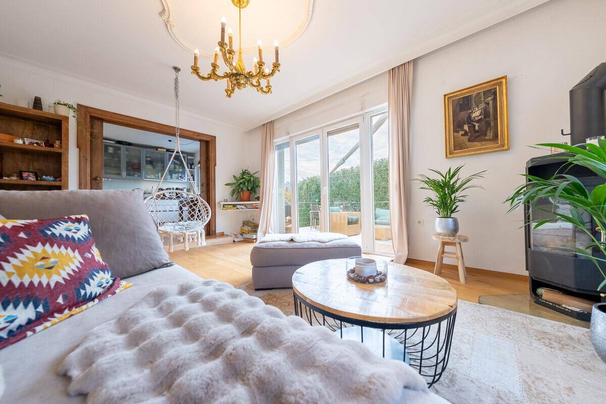 Gemütliches Wohnzimmer mit Holzboden, Kaminofen und einem Hängesessel, der zum Entspannen einlädt.
