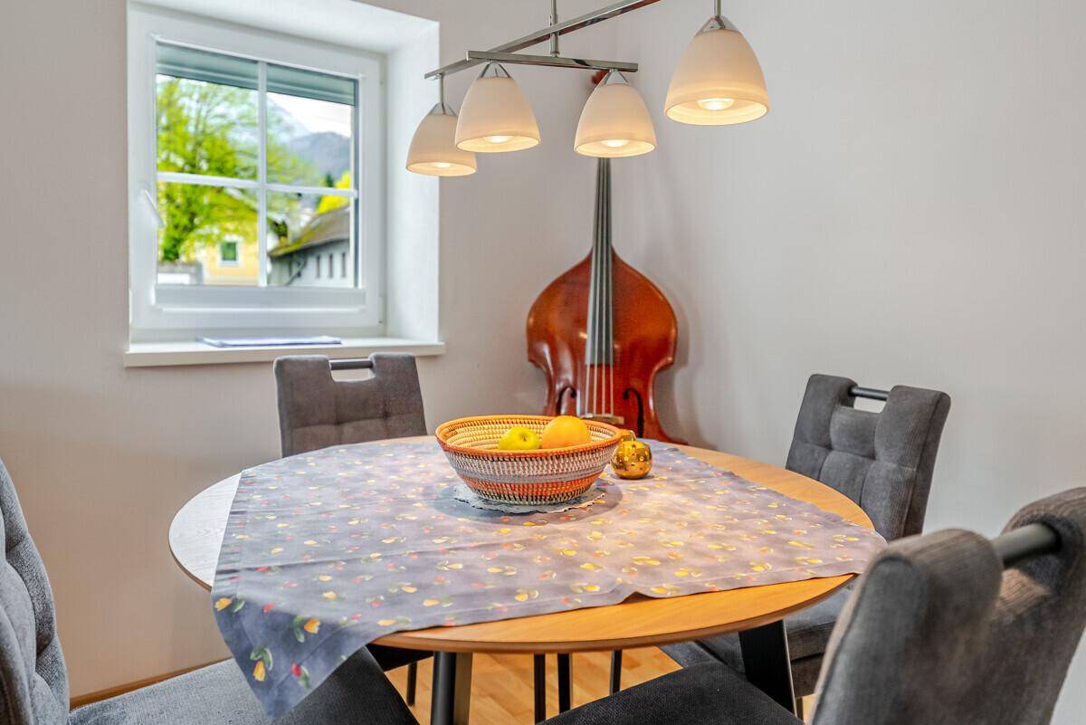 Gemütlicher Essbereich mit rundem Holztisch, Stühlen und Blick ins Grüne.