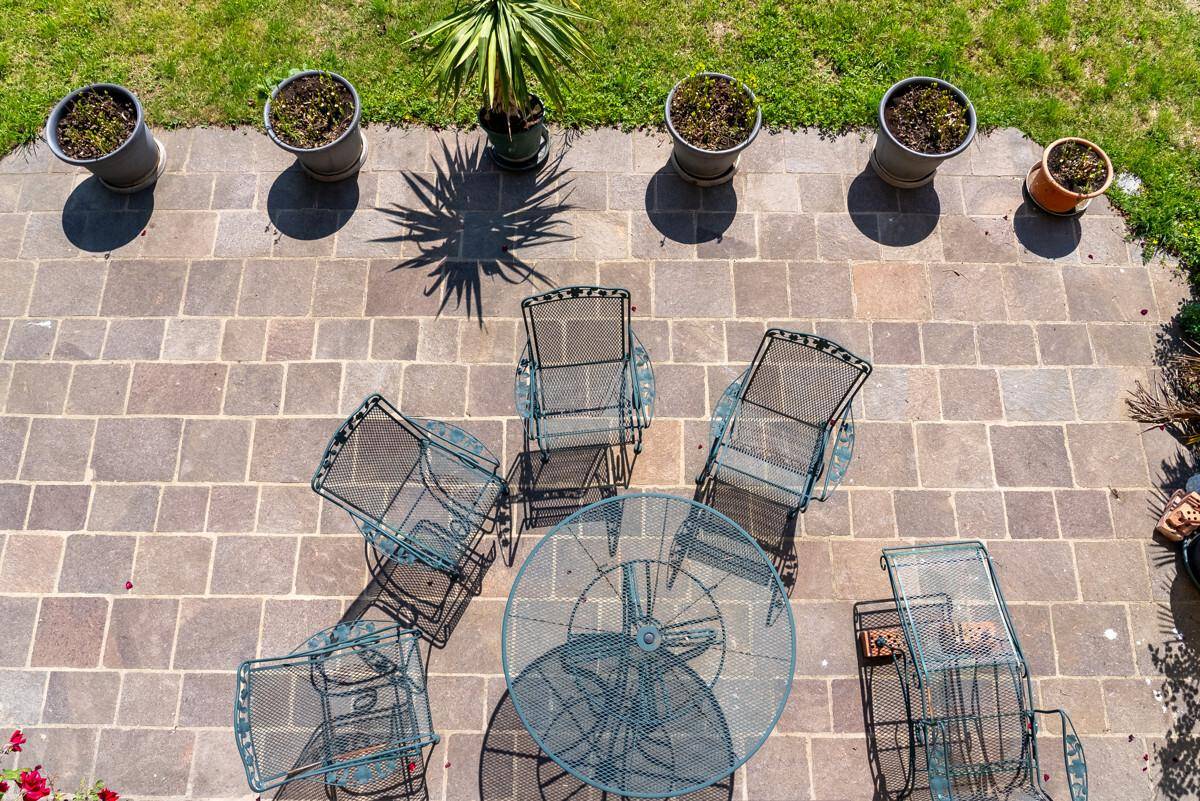 Gepflasterte Terrasse mit Metall-Gartenmöbeln und Topfpflanzen, ideal für entspannte Stunden im Freien.