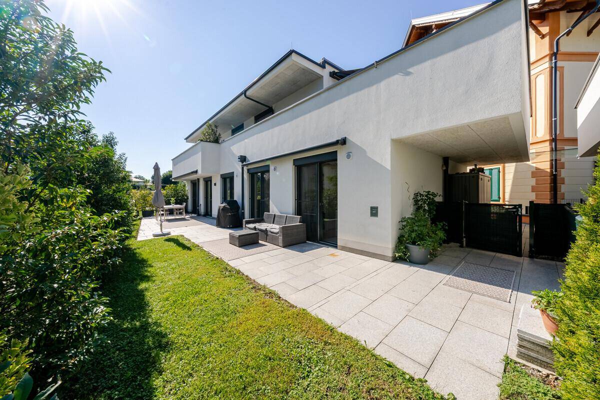 Außenansicht des Hauses mit großer Terrasse, gepflegtem Rasen und sonnigem Ambiente.