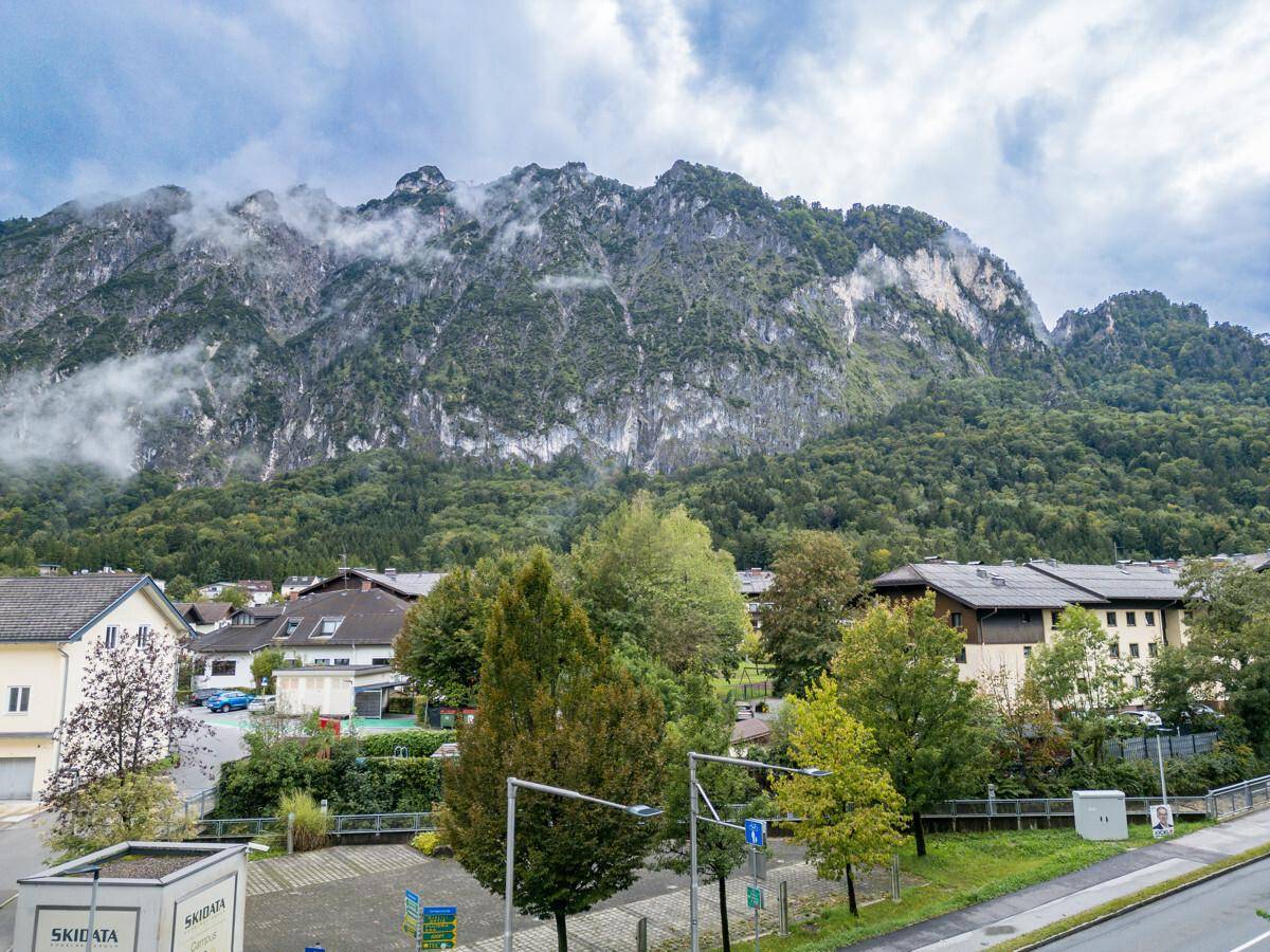 Malerischer Blick auf eine Berglandschaft mit bewaldeten Hängen und einer Siedlung im Tal.