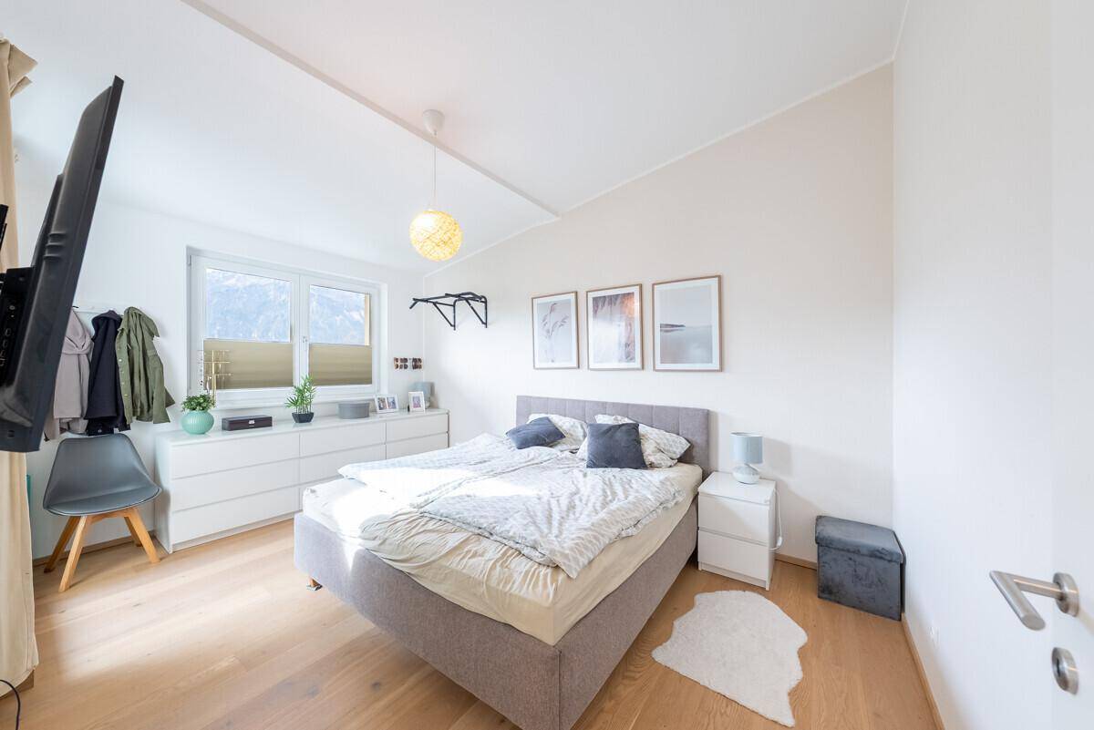 Gemütliches Schlafzimmer mit Doppelbett, Holzboden und Fenster mit Blick auf die Berge.