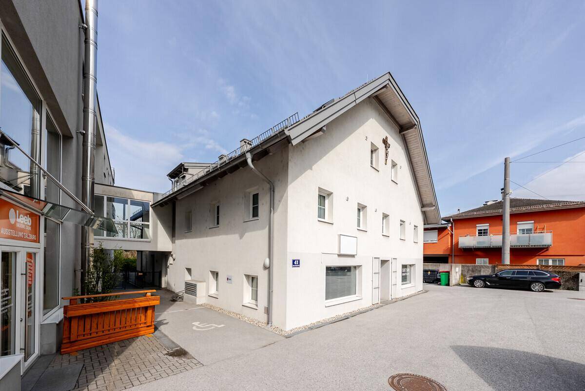 Ansicht der Gebäudefassade mit Parkplätzen und Zugang zu einem Geschäft.