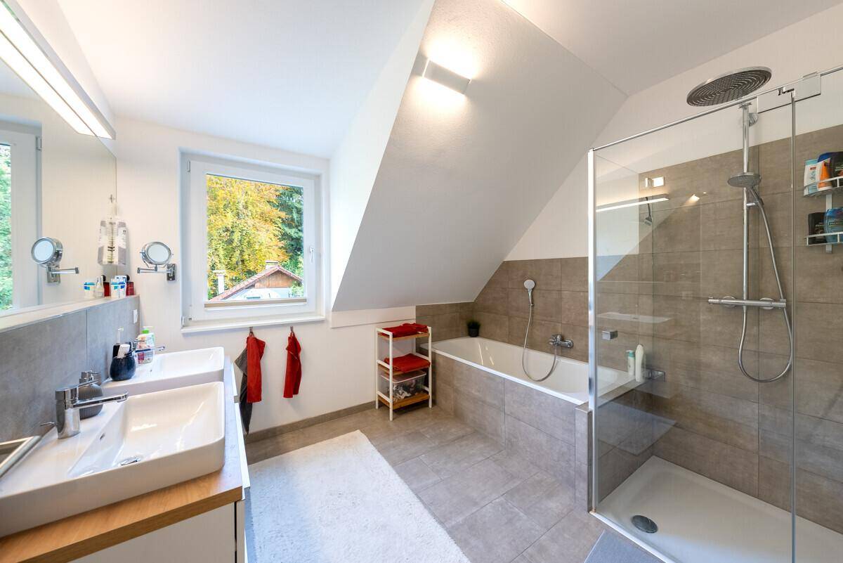 Modernes Badezimmer mit Doppelwaschbecken, Badewanne, begehbarer Dusche und Fenster.