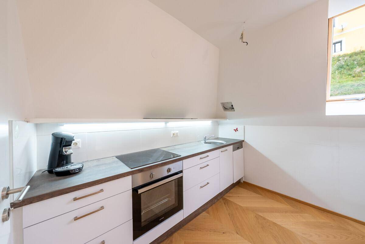 Kleine, moderne Küche im Dachgeschoss mit Einbaugeräten und Holzboden.