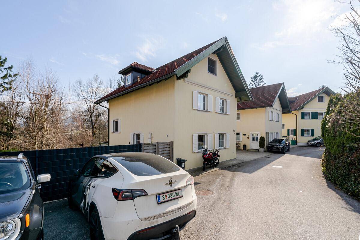 Einfamilienhaus mit Satteldach und Parkplätzen vor dem Gebäude.