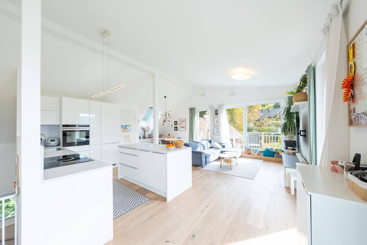 Heller, offener Wohn- und Essbereich mit moderner Küche, Holzboden und viel Tageslicht.