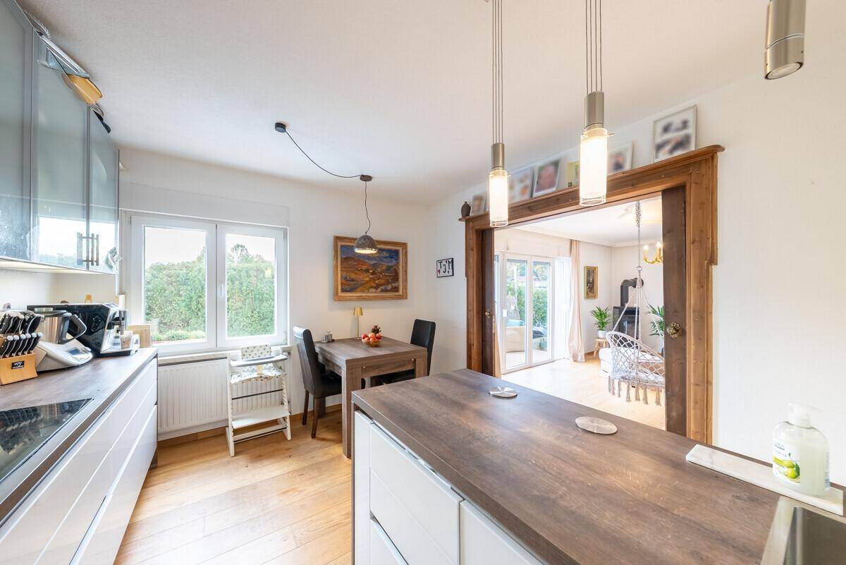 Moderne Küche mit Holzarbeitsplatte, Essbereich und offenem Zugang zum Wohnzimmer.