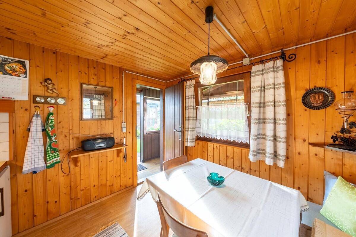 Helle Wohnküche mit Holzwänden, Essbereich und Zugang zum Eingangsbereich des Hauses.