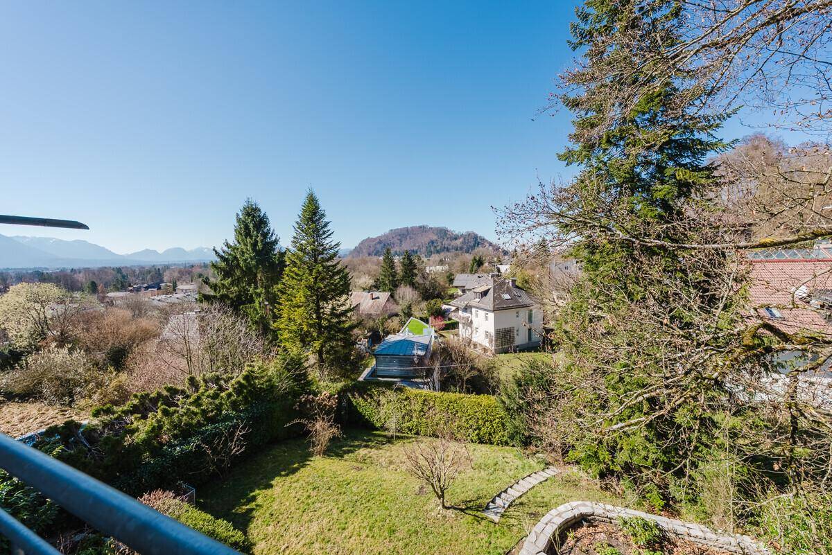 Balkon mit Blick auf den terrassierten Garten und die bewaldeten Hügel im Hintergrund.
